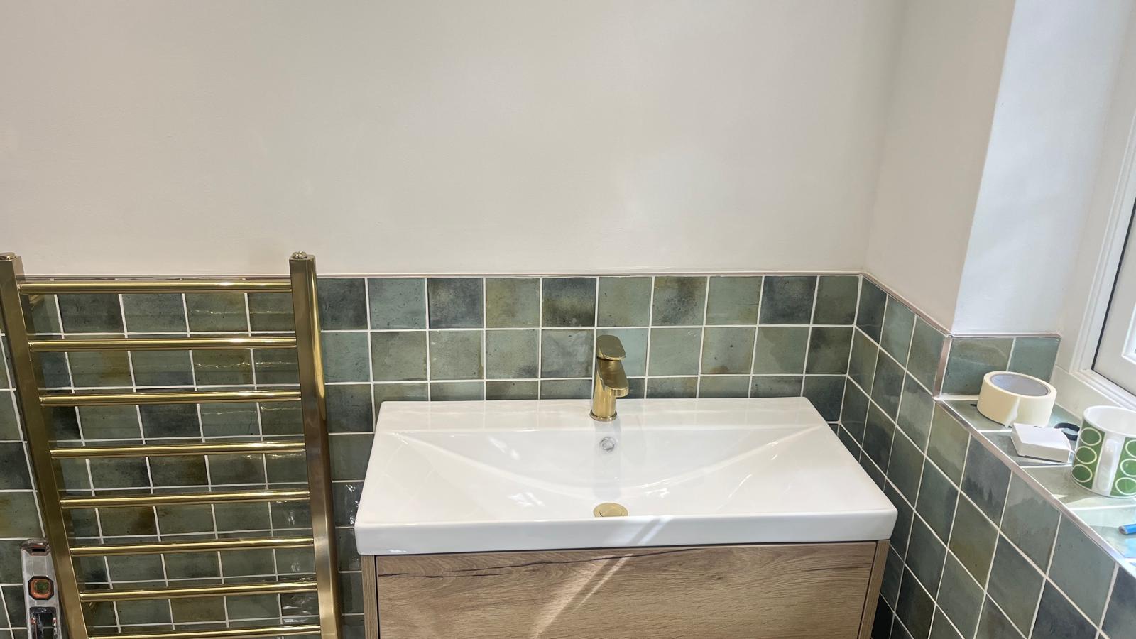 White basin with brass tap and tiled splashback