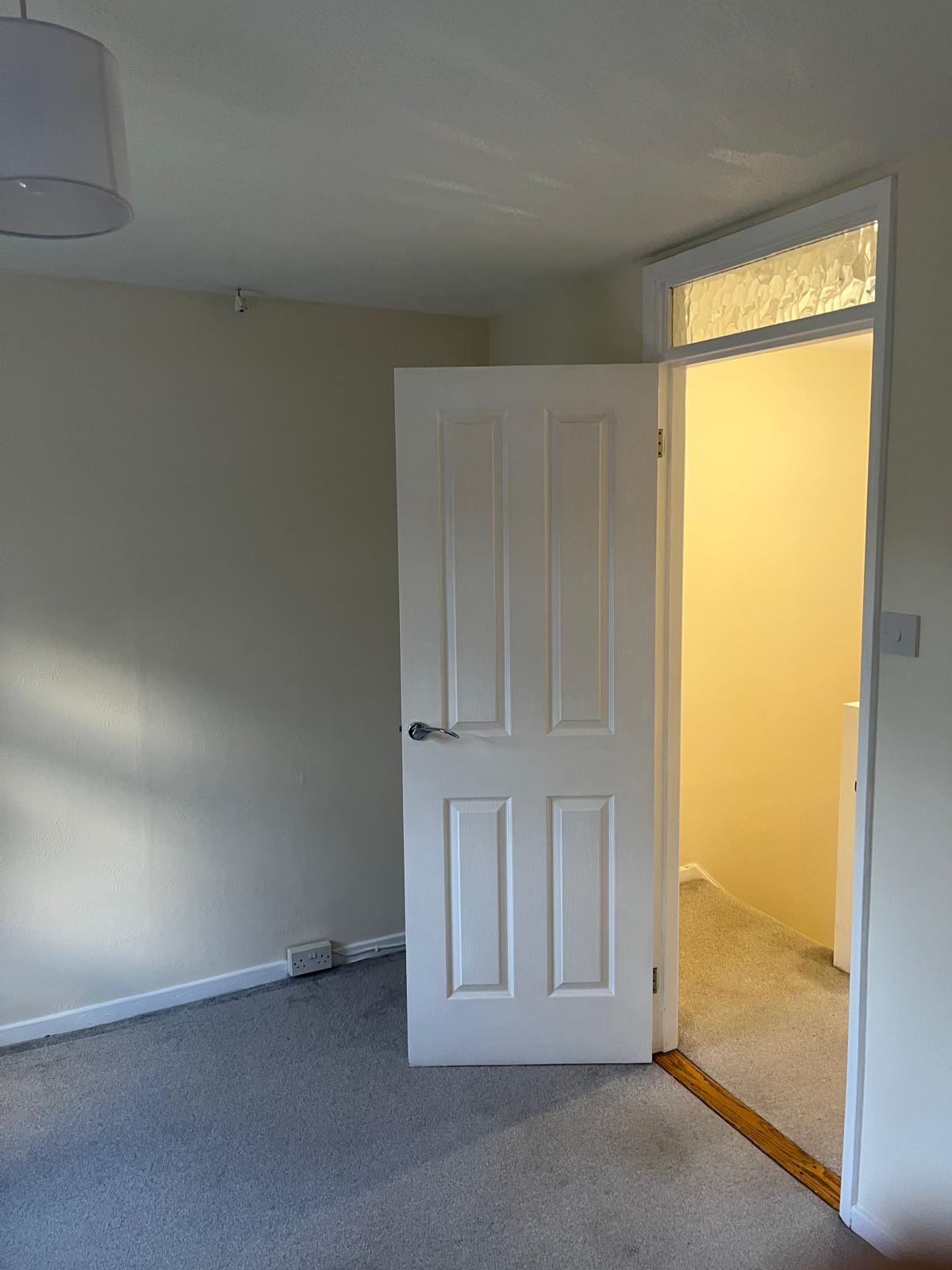 Bedroom door and frame painted white against cream walls