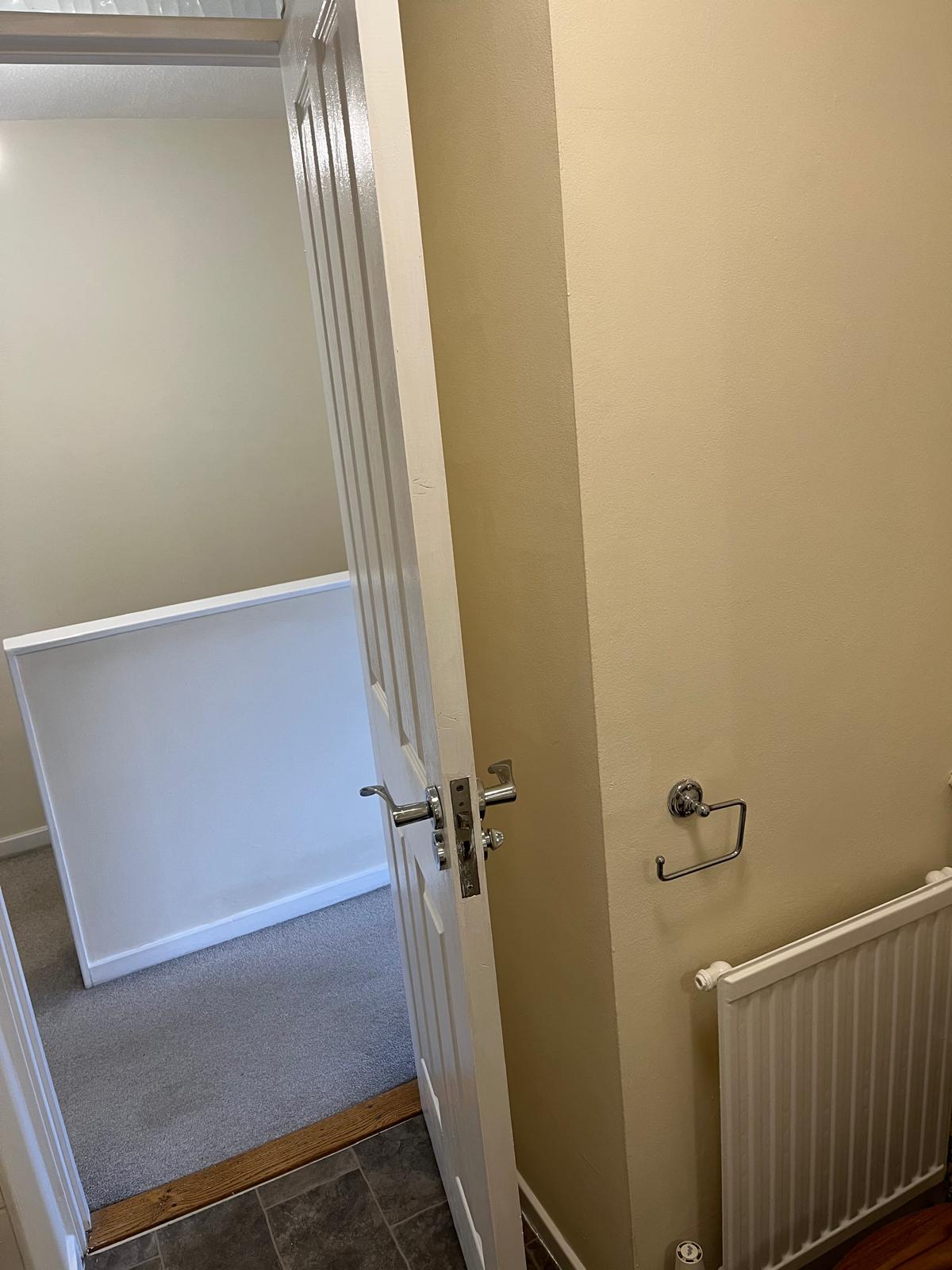 Cloakroom wall and landing seen through a white painted door