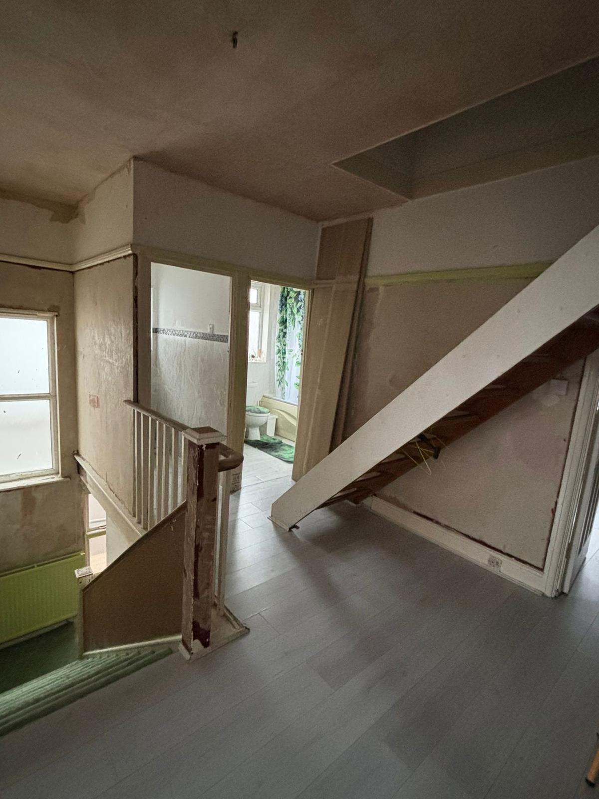 Before photo of the landing with bare, damaged walls